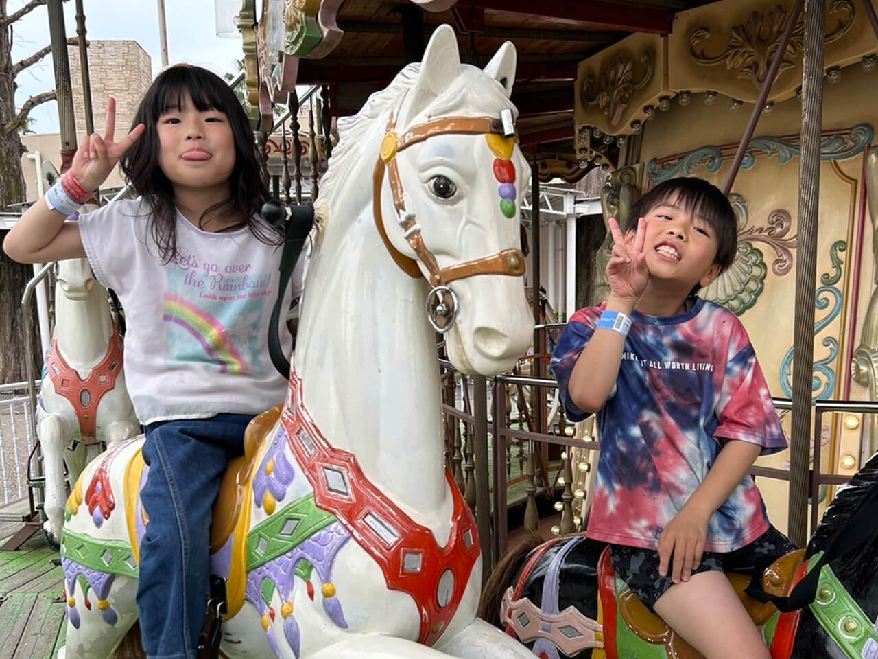 メリーゴーランドに乗ってピースをする子ども